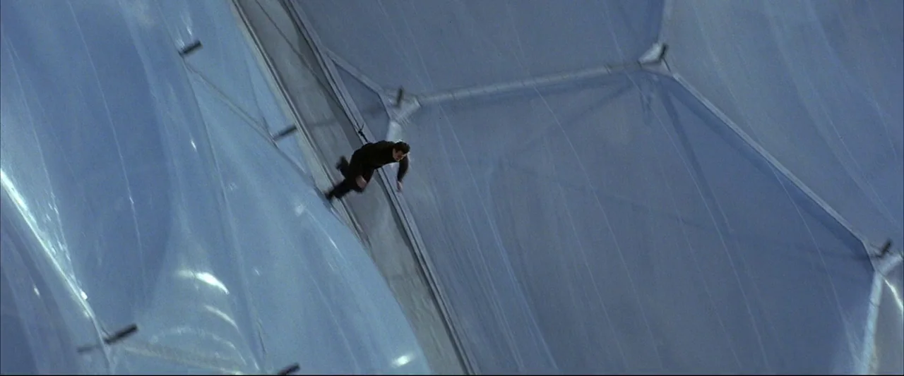 Die Another Day (2002) movie still: wide — A man in black slides down the curved surface of a translucent panelled dome. The exterior structure…