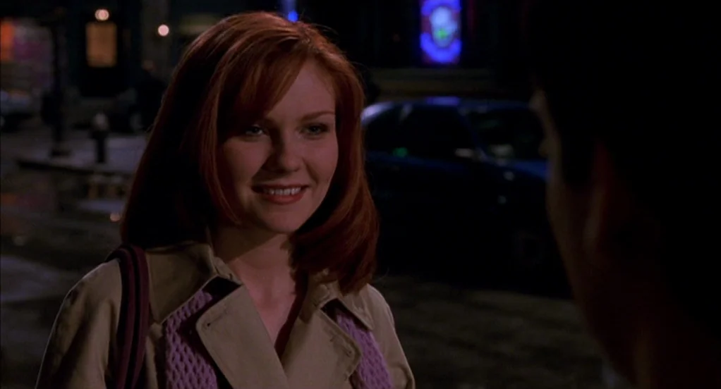 Spider-Man (2002) movie still: medium — A night time city street features a woman standing near a dark vehicle. The woman looks toward an unseen…