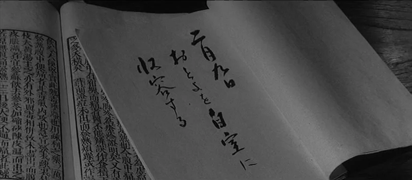 Red Beard (1965) movie still: closeup — An open antique book with detailed columns of traditional Japanese text lies flat. Large brush-style…
