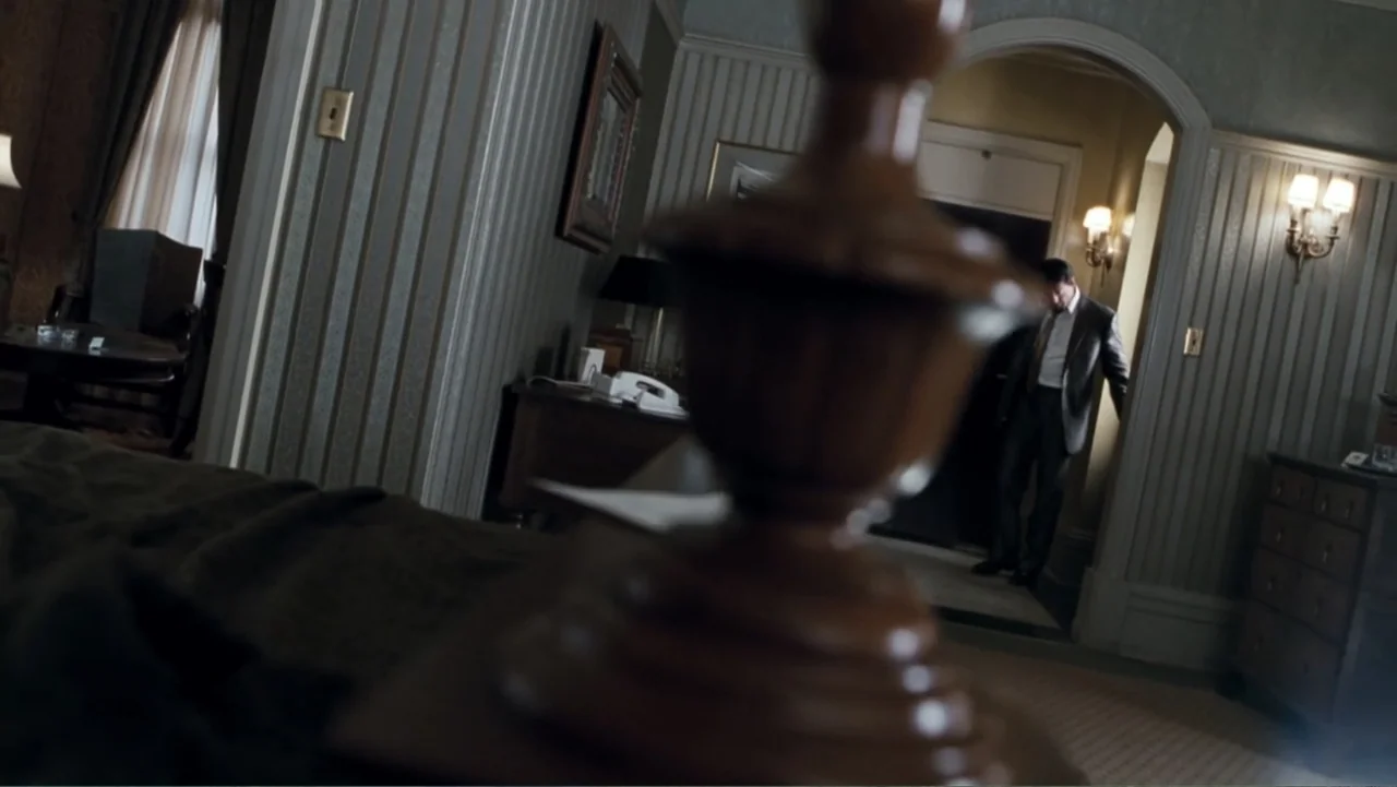 Get Carter (2000) movie still: medium — A classic hotel room features striped wallpaper and a dark arched doorway entry. A man in a suit stands in…