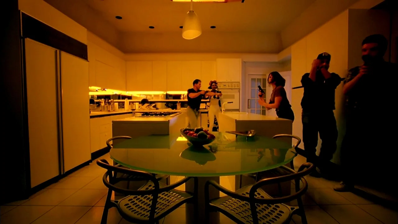 Belly (1998) movie still: wide — A modern, minimalist residential interior features clean white cabinetry and a glass dining table. Four individuals…