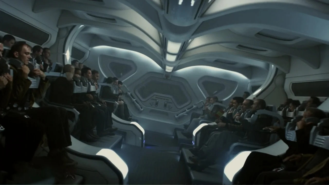 Total Recall (2012) movie still: wide — The interior of a sleek, white-walled spacecraft features rows of recessed passenger seats. A crowd of…