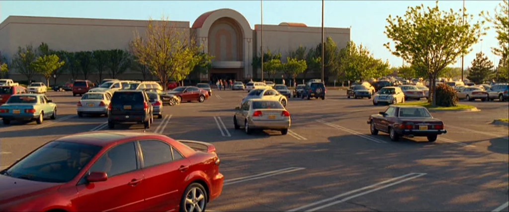 Observe And Report (2009) movie still: establishing — A sprawling outdoor parking lot sits in front of a massive, multi-entrance retail building.…