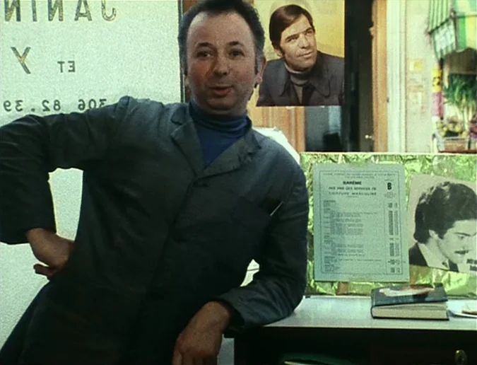 Daguerréotypes (1976) movie still: medium — A small retail shop interior features posters of male models on the walls. A middle-aged man in a work…