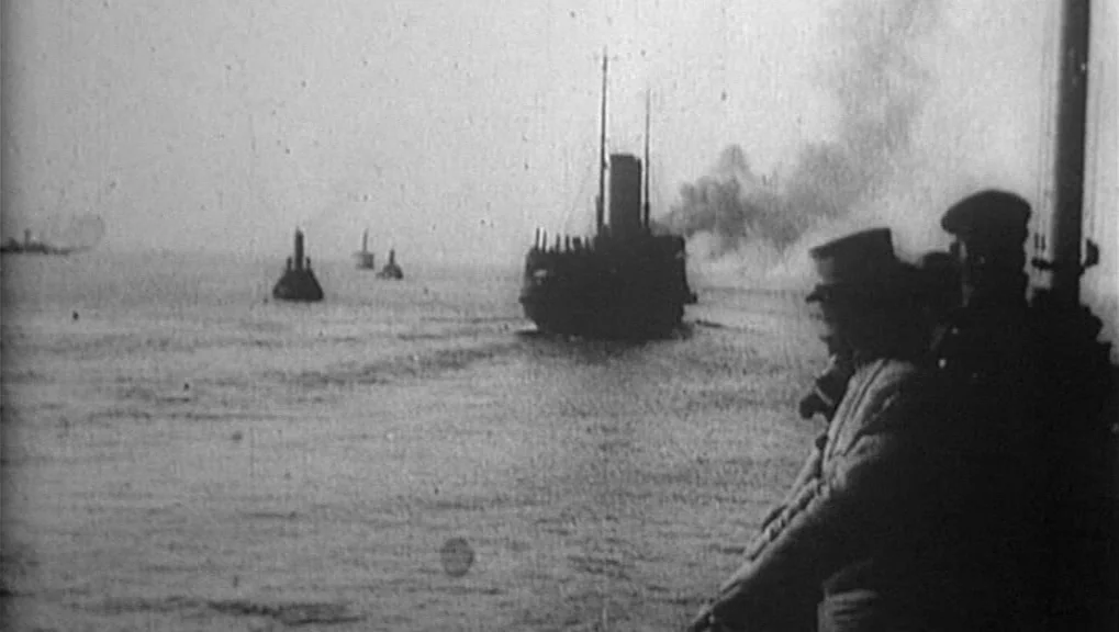 War Requiem (1989) movie still: wide — Two men in uniform look out from a ship deck across calm waters. Several steamships traverse the horizon…