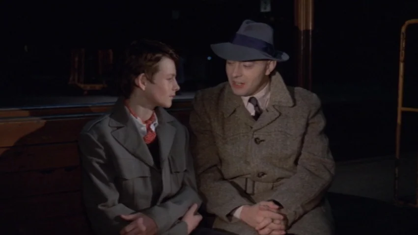Tenderness of the Wolves (1973) movie still: medium — A dark, empty train platform at night with horizontal wooden slats visible behind subjects. A…