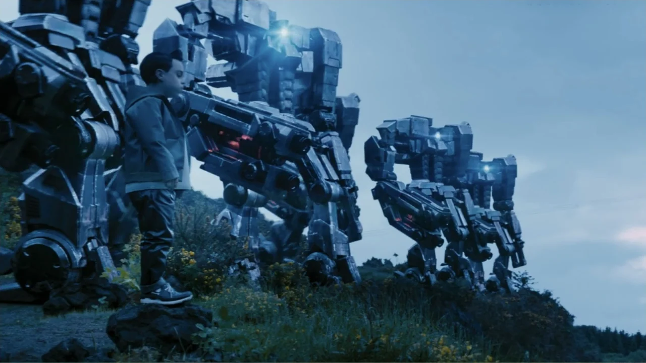 Robot Overlords (2015) movie still: fullbody — A grassy rocky hillside overlooks an overcast sky with three large metallic robots standing. A young…