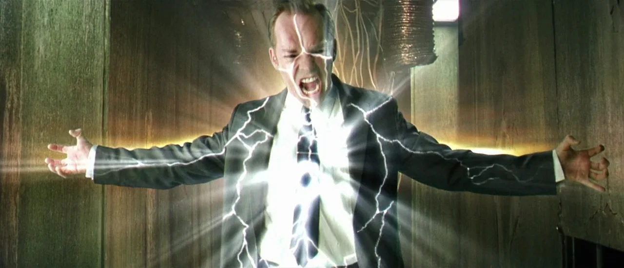 The Matrix (1999) movie still: medium — A narrow industrial passage features vertical wooden paneling and exposed metal ventilation ducts overhead.…
