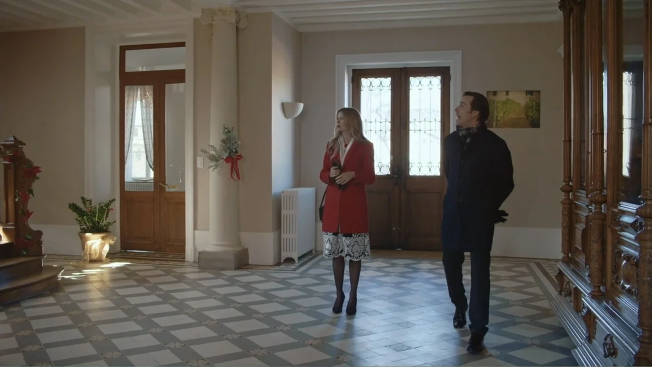 Driving Madeleine (2022) movie still: fullbody — An elegant entrance hall with checkered floor tiles and tall glass doors. A woman and a man walk…