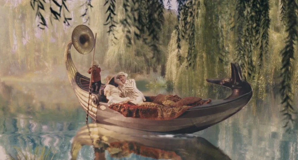 The Imaginarium of Doctor Parnassus (2009) movie still: wide — A boat resembling an Egyptian funerary barque floats on a calm, tree-lined lake. A…