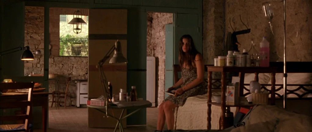 Stealing Beauty (1996) movie still: medium — A rustic bedroom features rough-hewn stone walls and simple wooden furniture in an old house. A young…
