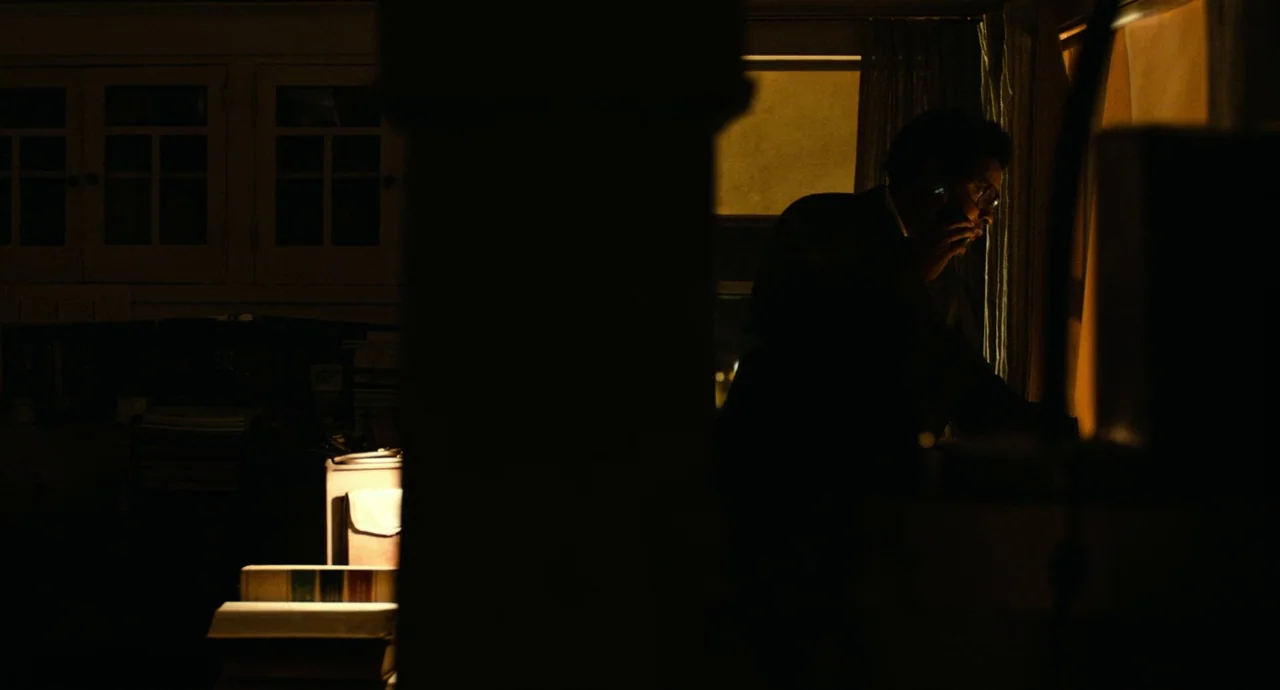Roman J. Israel, Esq. (2017) movie still: medium — A dimly lit room features a stack of books in the foreground and a large vertical pillar…