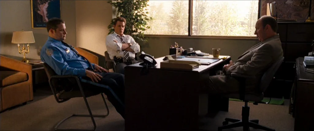 Observe And Report (2009) movie still: wide — A utilitarian professional space with a large desk and horizontal window blinds.