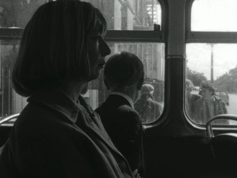 Children (1976) movie still: medium — A woman and a boy sit on a moving public transit vehicle during daytime. They look through the window at the…