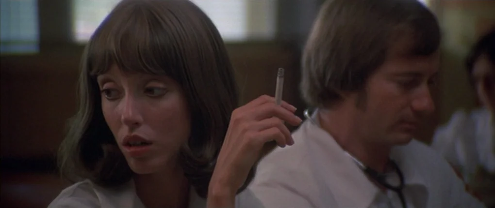 3 Women (1977) movie still: medium — A medical environment features two people sitting near each other in soft daylight. A woman looks to the side…