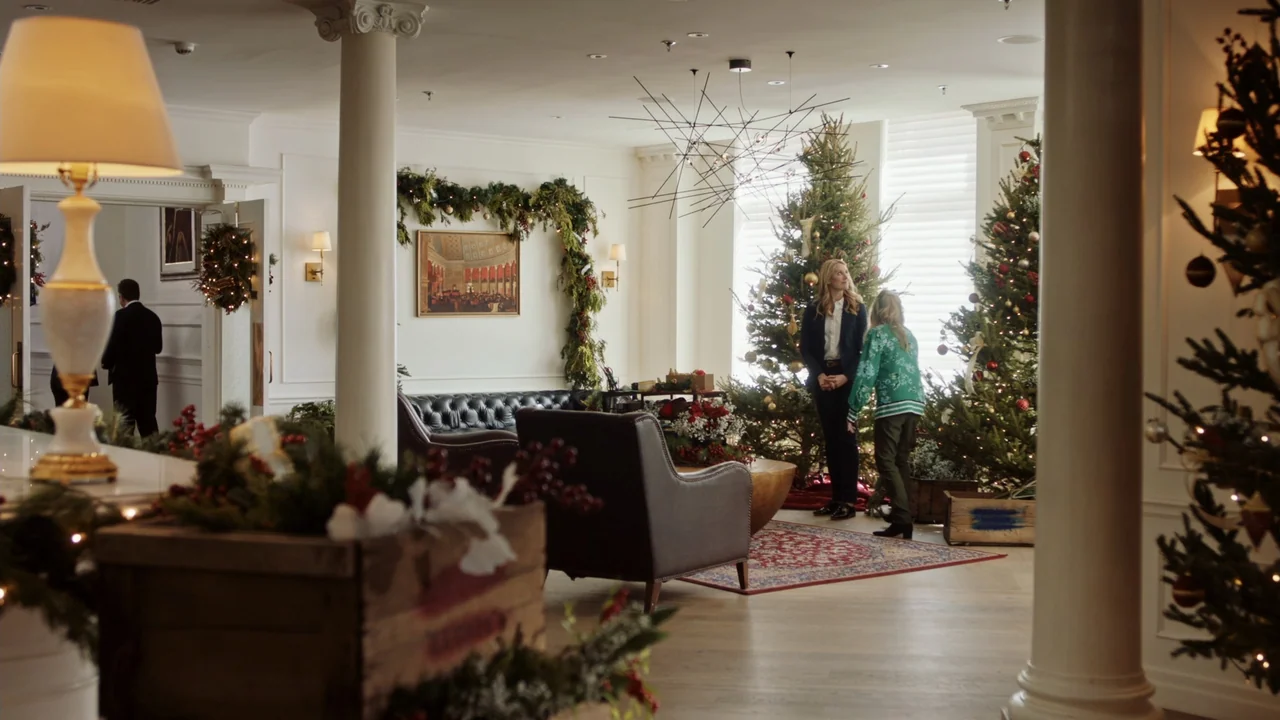 Christmas in Washington (2003) movie still: wide — An upscale hotel lobby is decorated for the holidays with Christmas trees and garlands. Two…
