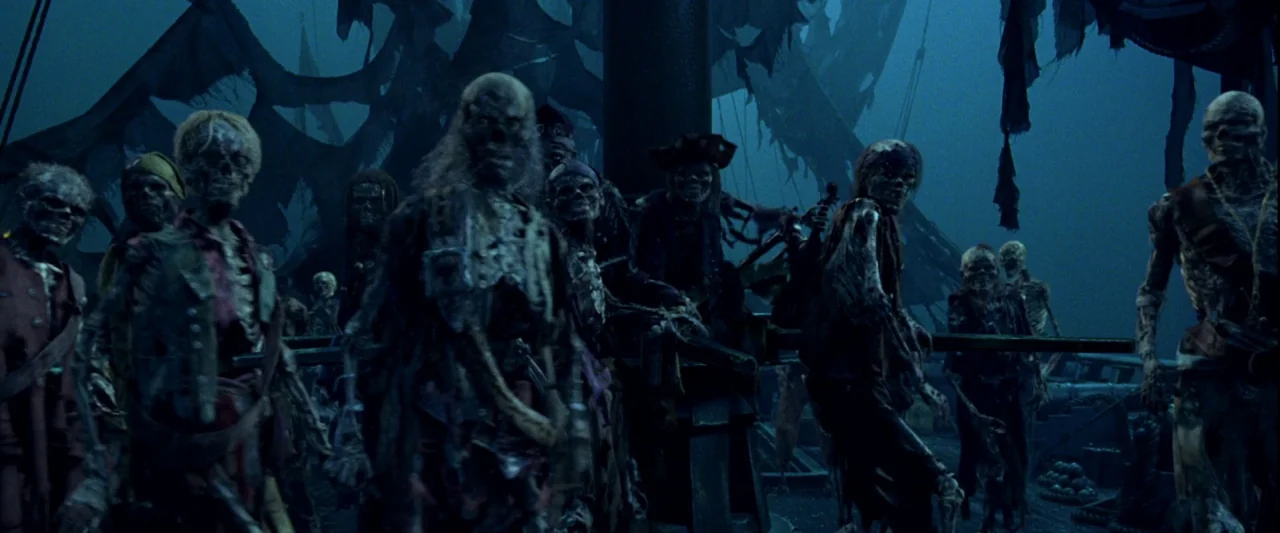 Pirates of the Caribbean: The Curse of the Black Pearl movie still: wide — A group of skeletons stand on the deck of a weathered, dark ship at…