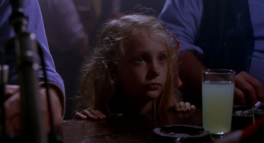 The Secret Of Roan Inish (1994) movie still: medium — A dark, dimly lit bar environment with patrons' arms visible in the foreground. A young blonde…
