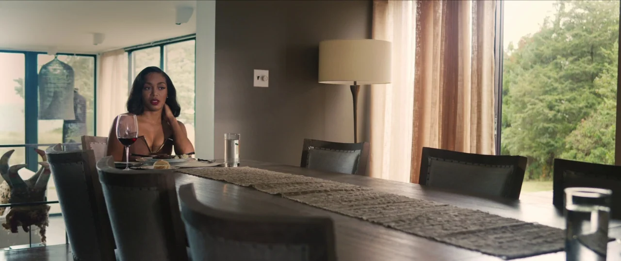 Da Sweet Blood of Jesus (2014) movie still: medium — A modern dining room features a long wooden table and floor-to-ceiling glass windows. A woman…