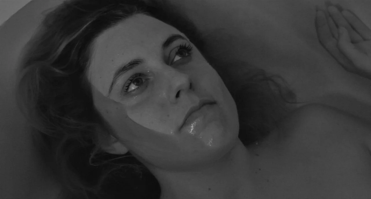 Frances Ha (2012) movie still: closeup — A close view of a woman submerged in water inside a bathtub. She lies with her head tilted back, looking…