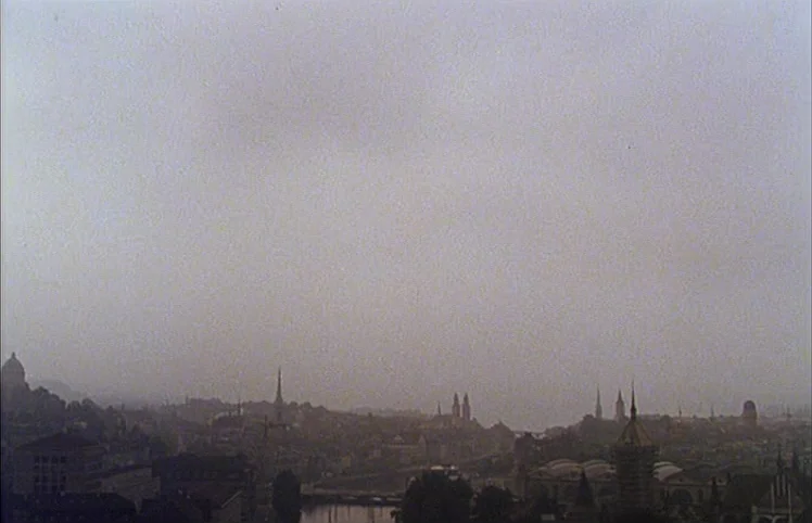 Lili Marleen (1981) movie still: establishing — A distant European city skyline is silhouetted against a vast, featureless grey sky. Numerous church…