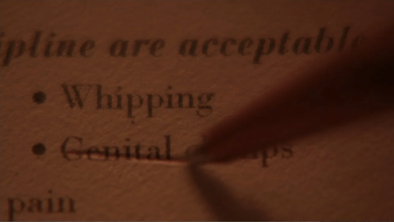 Fifty Shades of Grey (2015) movie still: closeup — A macro view of white paper with printed text under warm lighting. A sharpened pencil point moves…