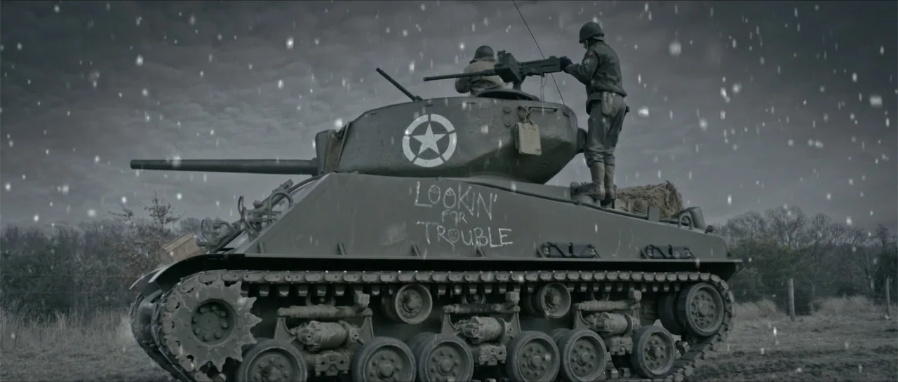 Battle of the Bulge (1965) movie still: fullbody — A field under a grey cloudy sky features an olive military tank in snow. Soldiers stand on the…