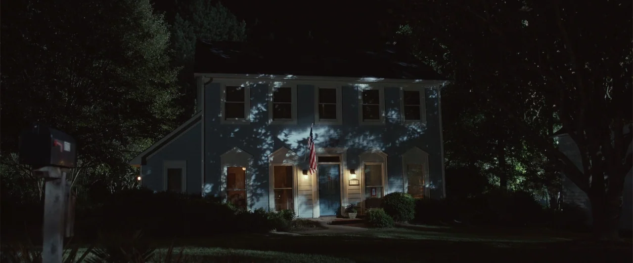 Max (2002) movie still: establishing — A two-story suburban house sits in darkness at night with trees surrounding it. The front door is illuminated…