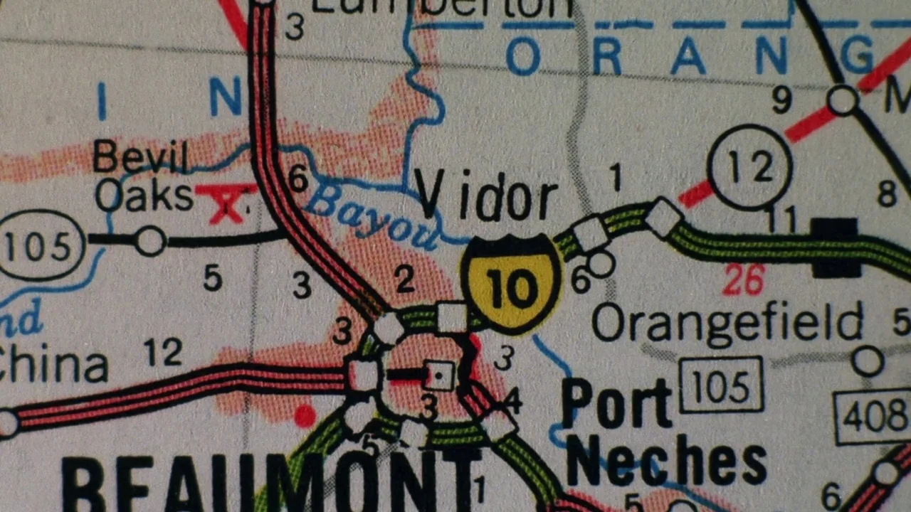 The Thin Blue Line (1988) movie still: closeup — A close-up view of a printed paper road map highlighting various Texas towns. The map displays…