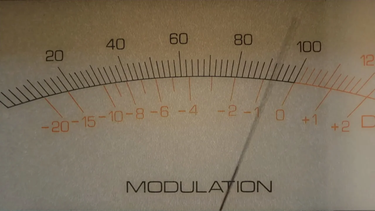 UFO Conspiracies: The Hidden Truth (2020) movie still: closeup — A close-up view shows the face of an analog modulation meter with numeric scales.…