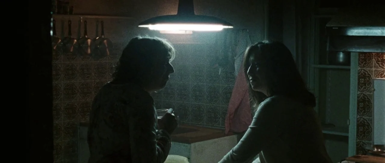 Alléluia (2014) movie still: medium — A dimly lit kitchen features patterned tiled walls and hanging cookware in the background. Two women stand…