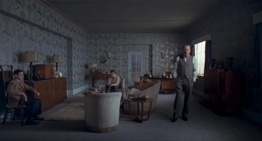 The King’s Speech (2010) movie still: wide — A spacious room features floral wallpaper and a collection of mid-century furniture pieces. Four…
