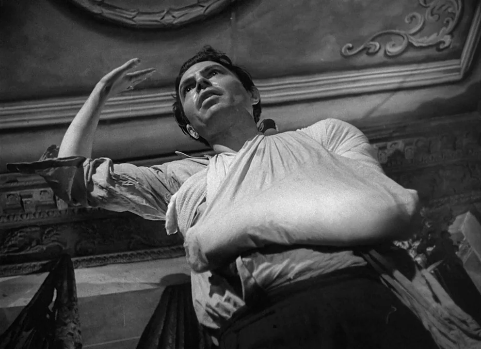 Odd Man Out (1947) movie still: medium — A room features a highly decorated molded ceiling with intricate architectural relief patterns. A man with…