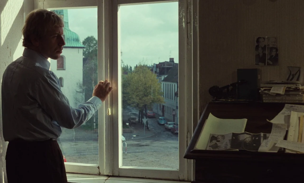 Wrong Move (1975) movie still: medium — A study features a wooden desk covered with scattered papers and a window view. A man stands looking out the…