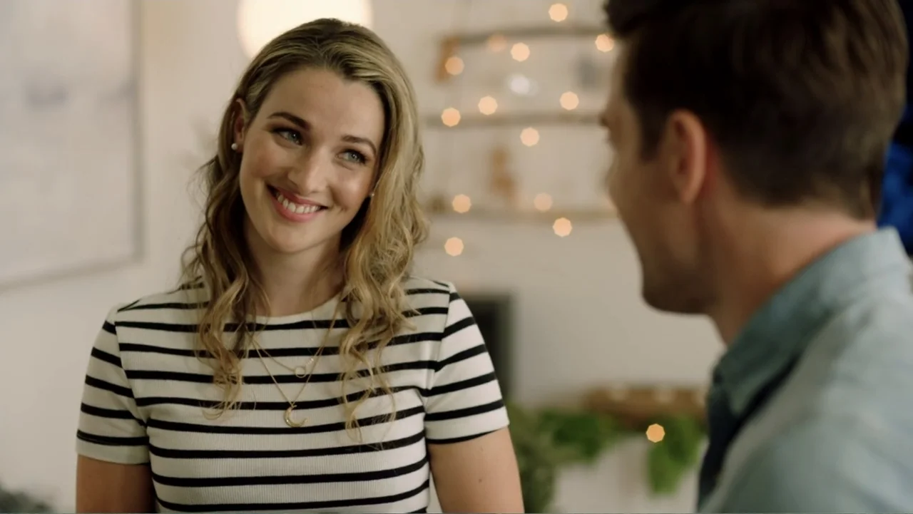 Ghosts of Christmas Past (2021) movie still: medium — A well-lit indoor space features string lights blurring in the background. A woman in a…