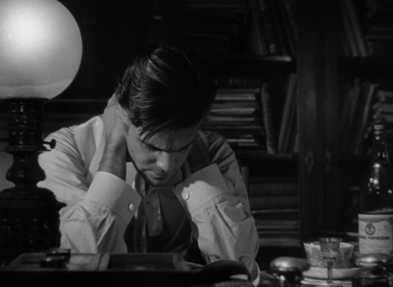Letter From An Unknown Woman (1948) movie still: medium — A dimly lit room contains wooden bookshelves packed with books in the blurred background.…