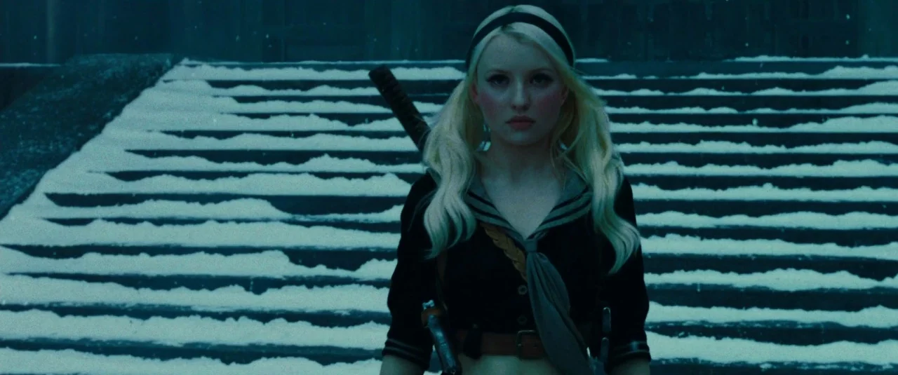 Sucker Punch (2011) movie still: medium — Wide outdoor stone steps are covered in a light layer of falling snow. A young woman with blonde hair…