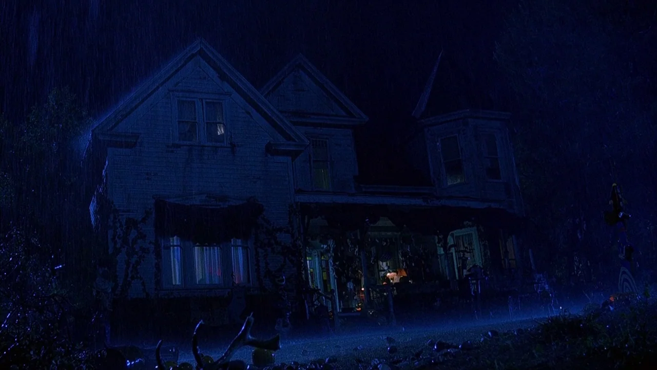 House of 1000 Corpses (2003) movie still: establishing — A two-story Victorian house is viewed from the yard during a heavy night rainstorm. Rain…