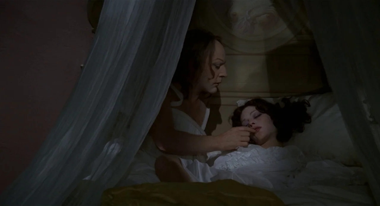 Fellini’s Casanova (1976) movie still: medium — A person in a white gown leans over a woman sleeping in a bed. She is under a draped canopy with a…