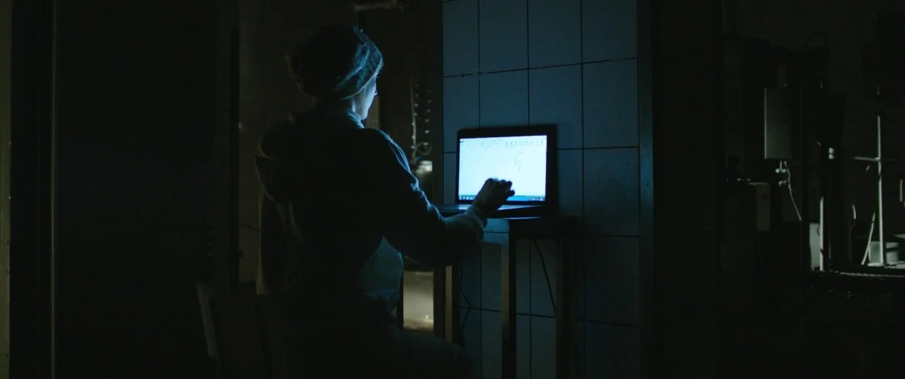 On Body and Soul (2017) movie still: medium — A dark, dimly lit room features a person silhouetted against a bright computer screen. The subject…