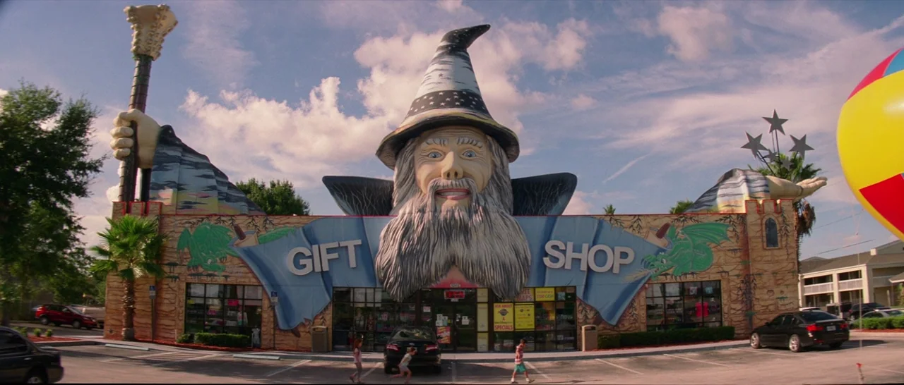 The Florida Project (2017) movie still: wide — A roadside gift shop features a giant molded wizard head above the entrance doors. The structure is…