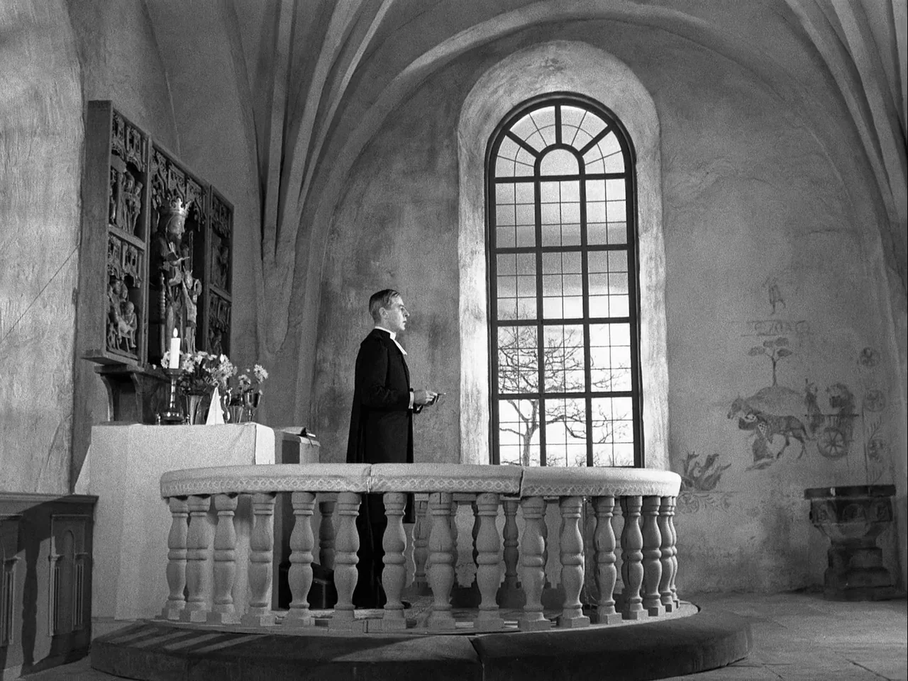 Winter Light (1963) movie still: fullbody — A stone-walled interior space features vaulted ceilings and a tall arched window. A man in clerical…