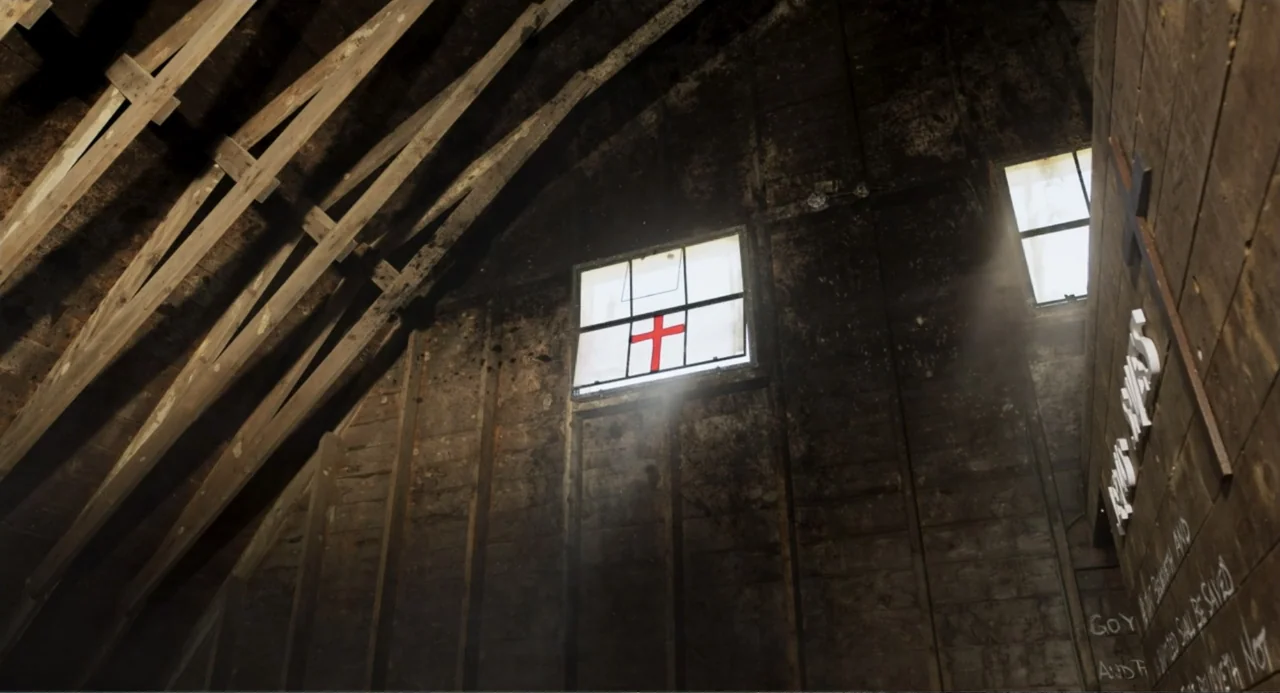 Salvation (2025) movie still: establishing — A dark, unfinished attic features exposed wooden rafters and weathered timber walls. Two small windows…