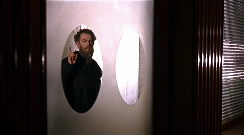 Juliet of the Spirits (1965) movie still: medium — A corridor features a wall with two oval-shaped frosted glass windows. An older man stands behind…