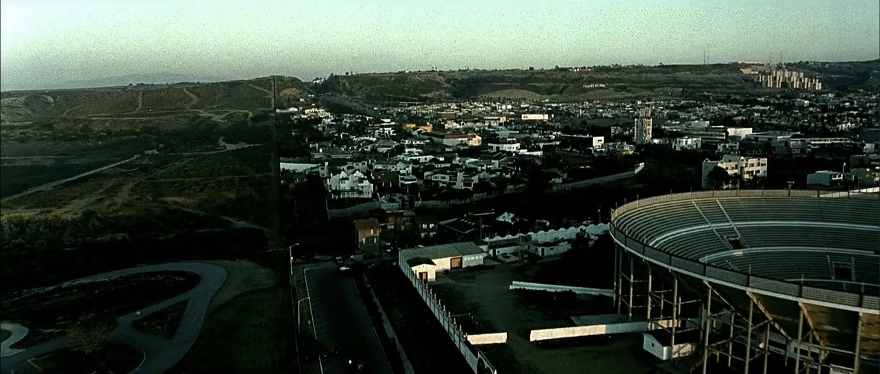 A Man Apart (2003) movie still: establishing — A sprawling coastal city sits nestled against rolling hills during the late afternoon. A large…