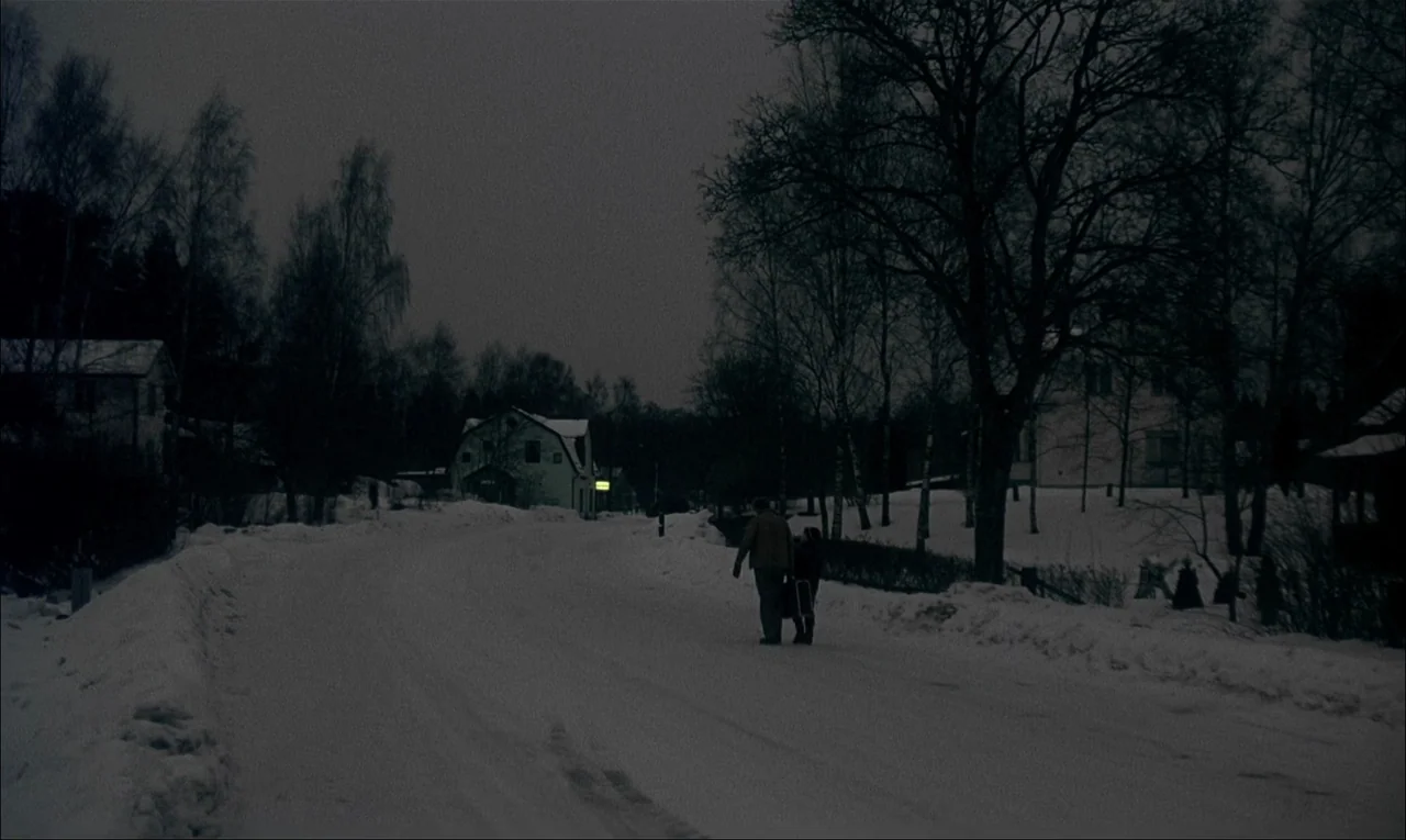 My Life As A Dog (1985) movie still: wide — A quiet residential street is covered in a thick layer of blue-tinted snow. Two people walk away from…