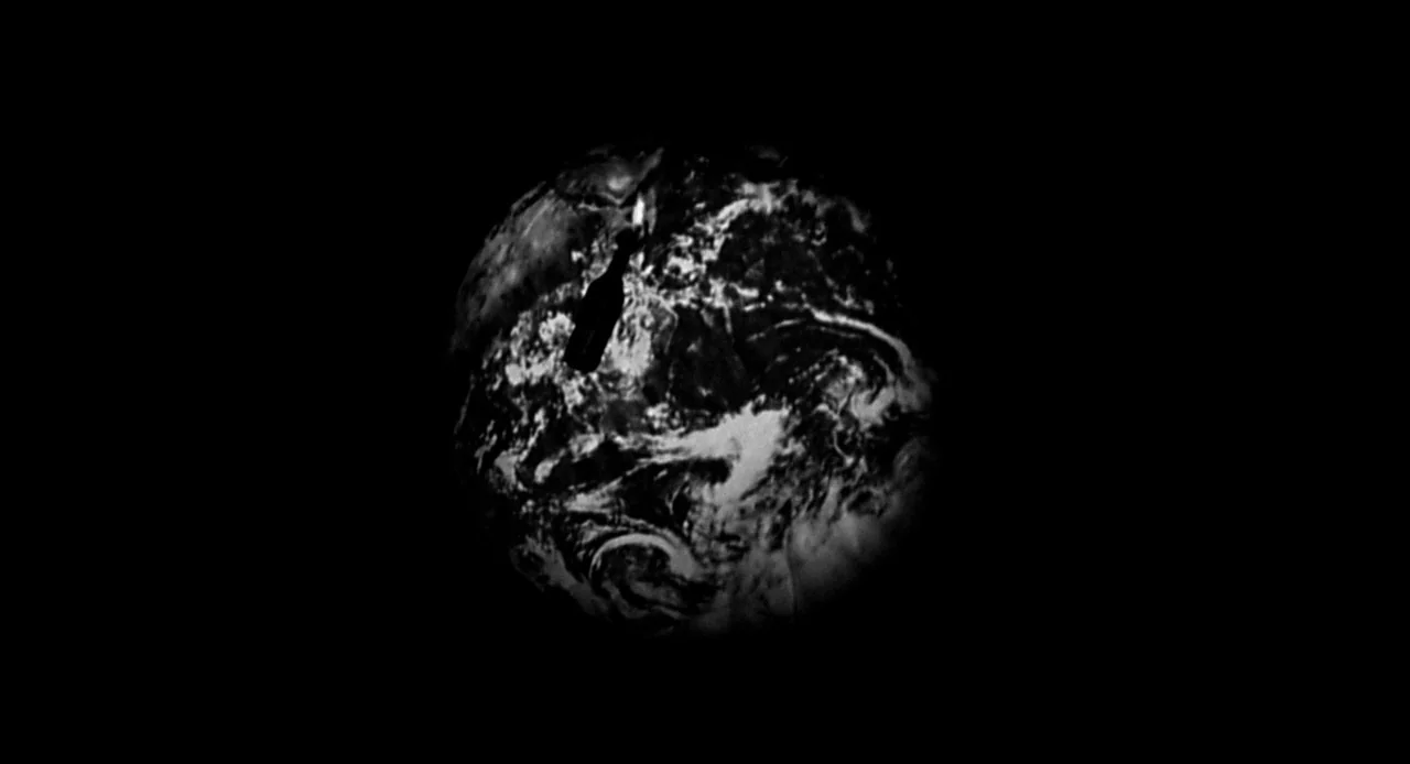 La Haine (1995) movie still: wide — The Earth is visible against a vast field of deep black empty space. A silhouette of a dark bottle floats in the…
