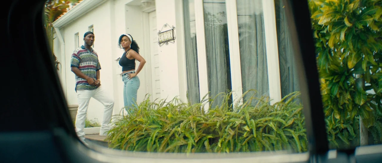 Moonlight (2016) movie still: fullbody — A white stucco house features a glass-paned front door and large windows. A man and a woman stand on the…