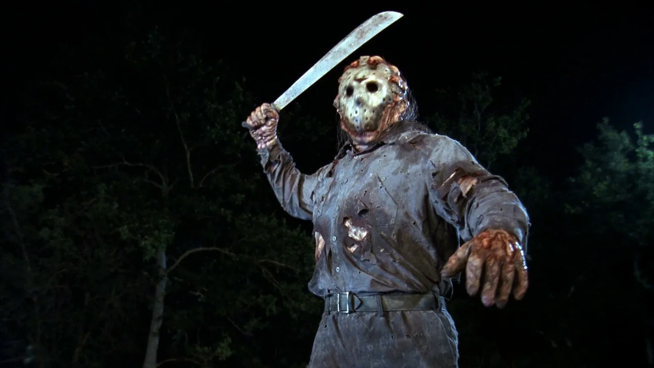 Jason Goes To Hell (1993) movie still: medium — A dark, nocturnal setting with indistinct trees silhouetted against a black sky. A man wearing a…