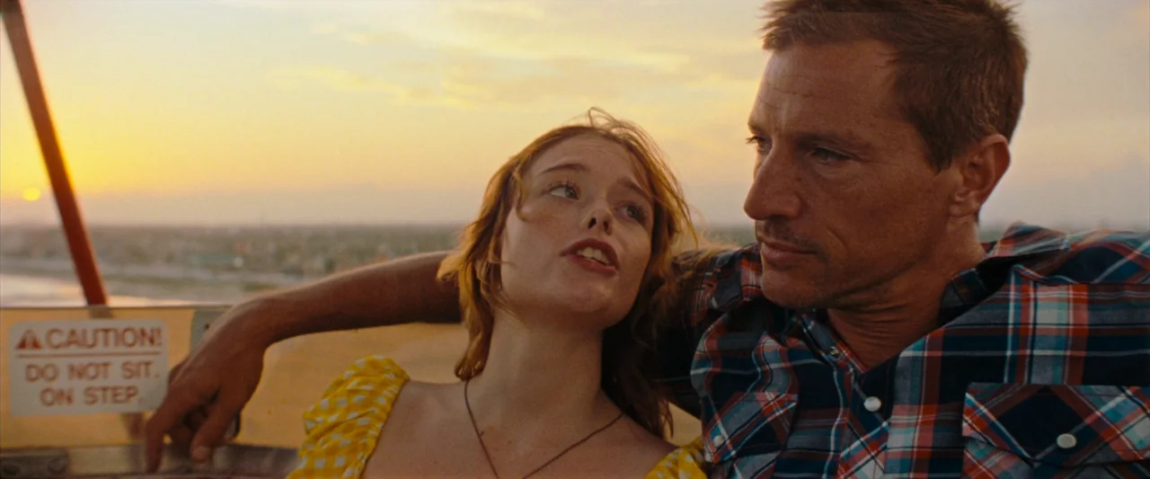 Red Rocket (2021) movie still: medium — A man and woman sit together inside a Ferris wheel carriage at sunset. They are suspended in the air, with…